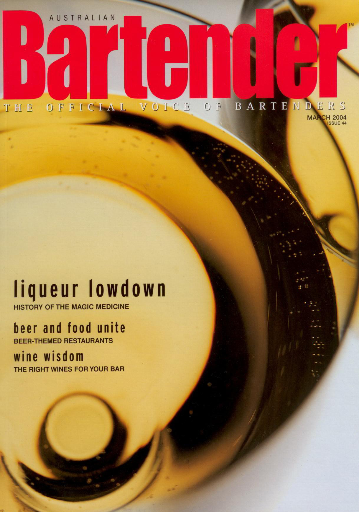 Close-up overhead view of a glass of golden liquid with bubbles, featured on the cover of Australian Bartender magazine.